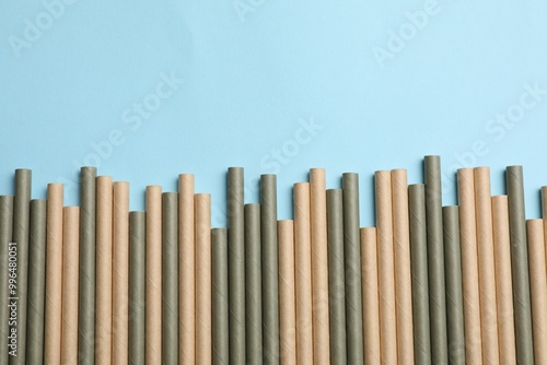 Bamboo drinking straws on light blue background, top view. Space for text