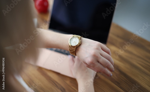 Close-up of office worker woman look at time on wristwatch and wait end of shift. Female late and check time, in rush home. Job, accessory, timing concept photo