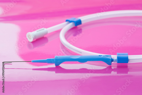 Parts of sterile, single-use vascular access guidewire to guide the catheter into place during central venous catheter insertions on pink background photo