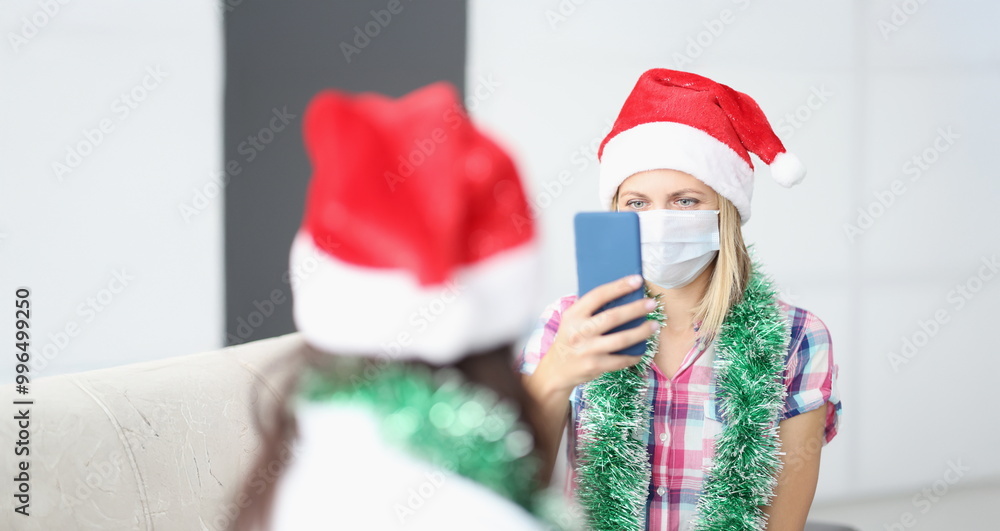 Obraz premium Portrait of woman take video of friend on smartphone, content for internet channel. Celebrating new year with friend during quarantine. Friendship concept