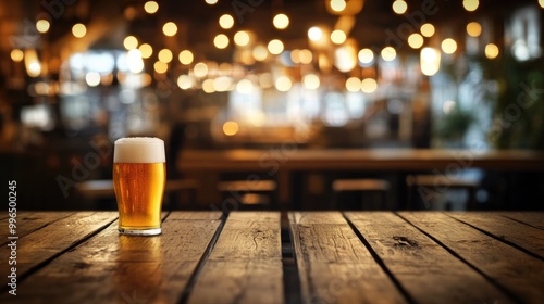 Empty wooden table with a glass of light beer set against a defocused background featuring bokeh lights and a blurred ambiance of a cafe and pub photo