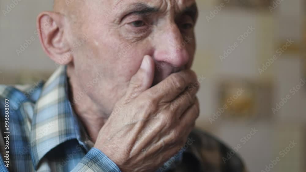 Caucasian pensioner 70-79 years old coughs heavily into his fist while inside, portrait of an elderly man coughing Caucasian pensioner 70-79 years old coughs heavily into his fist while inside, portrait of an elderly man coughing