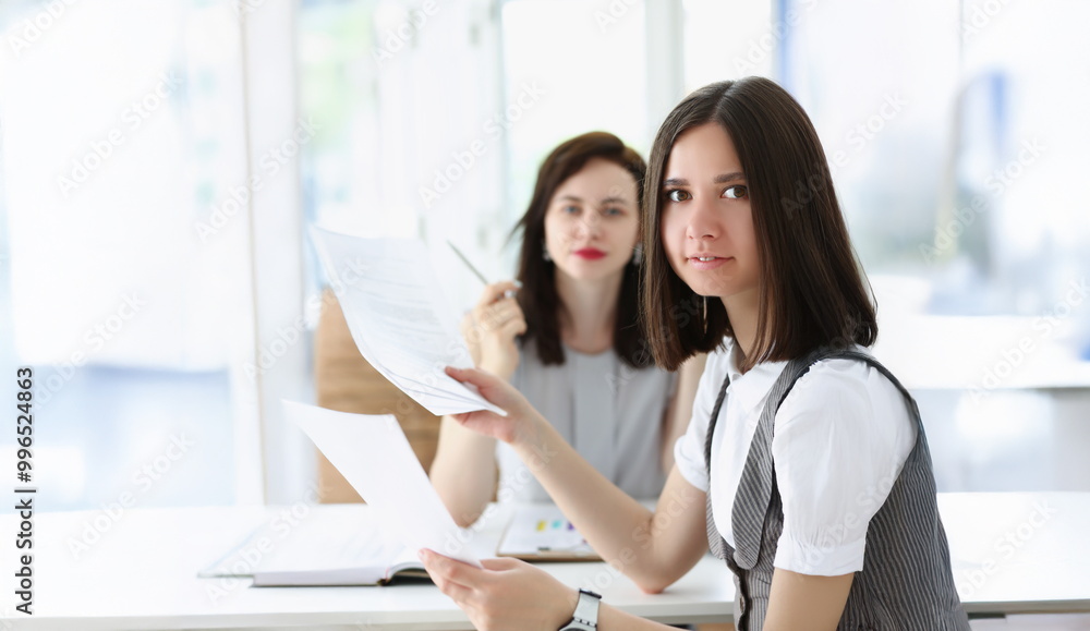 Portrait of business women working on monthly report surrounded with bunch of papers. Colleagues workers in company office. Business, corporate concept Portrait of business women working on monthly report surrounded with bunch of papers. Colleagues workers in company office. Business, corporate concept