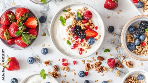 A fresh and healthy breakfast spread with yogurt, granola, fresh fruit, and nuts, presented in a clean and modern setting