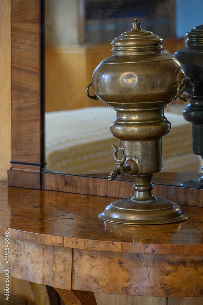 An old teapot standing by a mirror.
An old teapot standing by a mirror.
