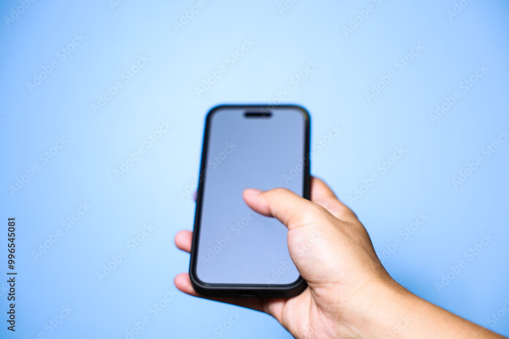 Closeup of hand holding or using smartphone on blue background. Closeup of hand holding or using smartphone on blue background.