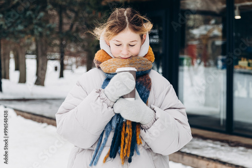 Young girl enjoying a cozy drink during a snowy walk photo