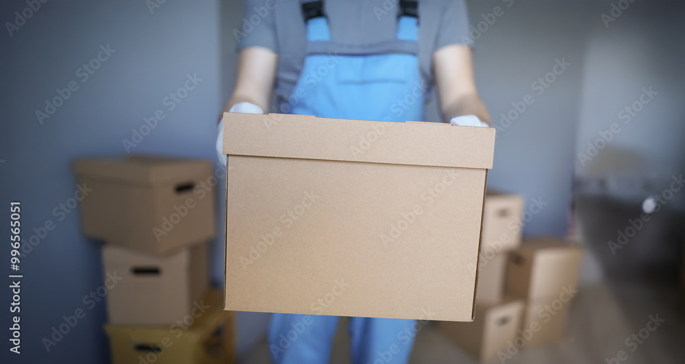 Close-up of worker loading cardboard boxes with owners belongings to new apartment. Guy from delivery service help with relocation. Loader, moving concept