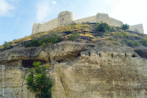 Fortification architecture in Turkish Mesopotamia: defensive walls and towers of the Gaziantep castle and a rock with ancient man-made caves beneath it. Architectural heritage of Turkey.