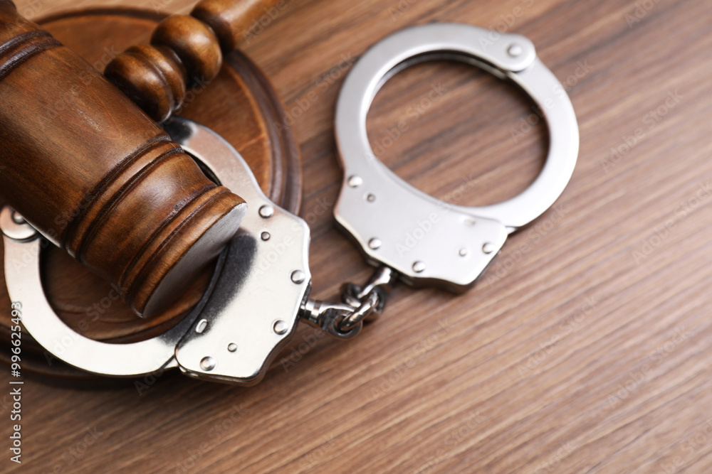 Obraz premium Judge's gavel and handcuffs on wooden table, top view