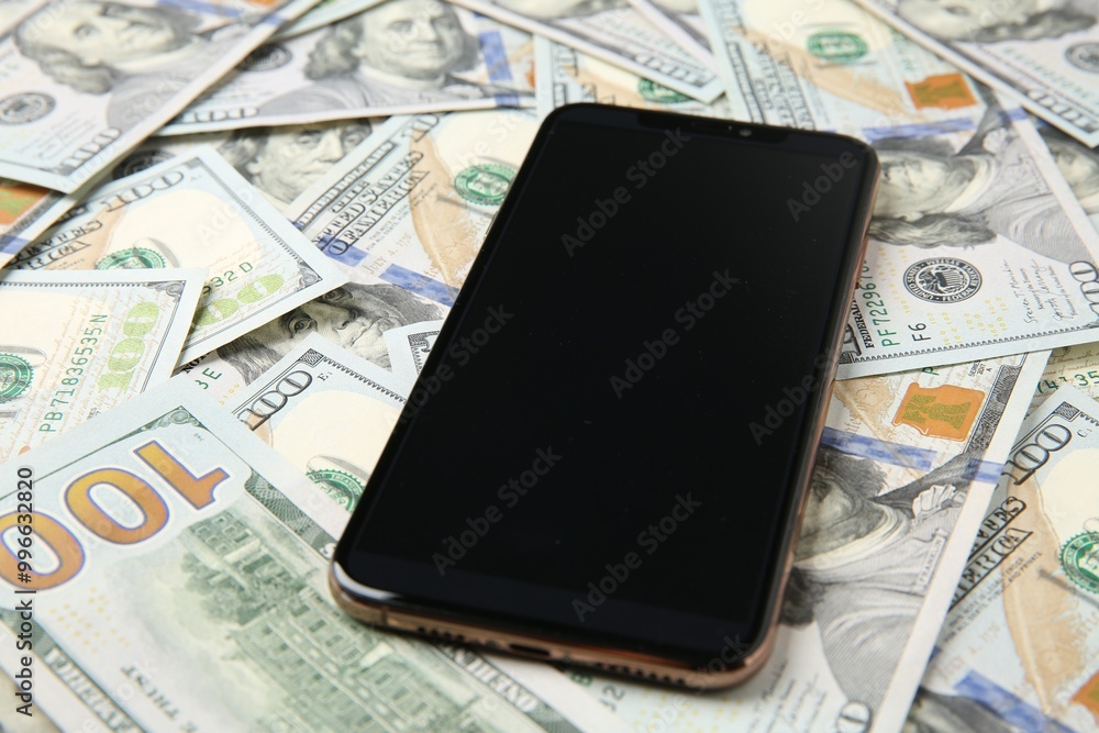 Modern smartphone on dollar bills, closeup view Modern smartphone on dollar bills, closeup view