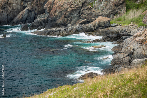 A cliff above water with waves crashing on the rocks