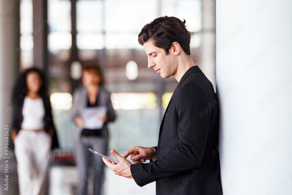 Diverse businesspeople are standing at the building corridor and talking together. Diverse businesspeople are standing at the building corridor and talking together.