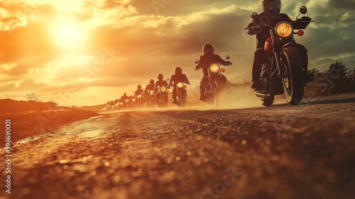 A group of motorcyclists ride down a dusty road at sunset. photo