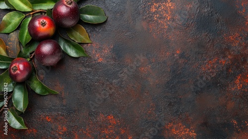 A composition of red fruits and green leaves on a textured dark background. photo