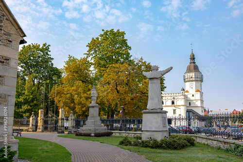 Statue of Saint with Arms Raised and Szydłowiec Tower in the Background in Szydłowiec, Poland photo