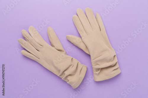 Beige gloves on color background, top view