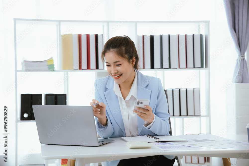 An Asian businesswoman works at her desk in an office. She works hard on her laptop, communicates online, manages her tasks, and easily balances her career. An Asian businesswoman works at her desk in an office. She works hard on her laptop, communicates online, manages her tasks, and easily balances her career.