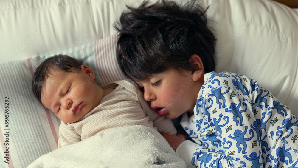 Adorable baby and older brother snuggle together on a bed, sharing a sweet nap time moment, surrounded by cozy blankets and pillows in a warm, inviting room Adorable baby and older brother snuggle together on a bed, sharing a sweet nap time moment, surrounded by cozy blankets and pillows in a warm, inviting room