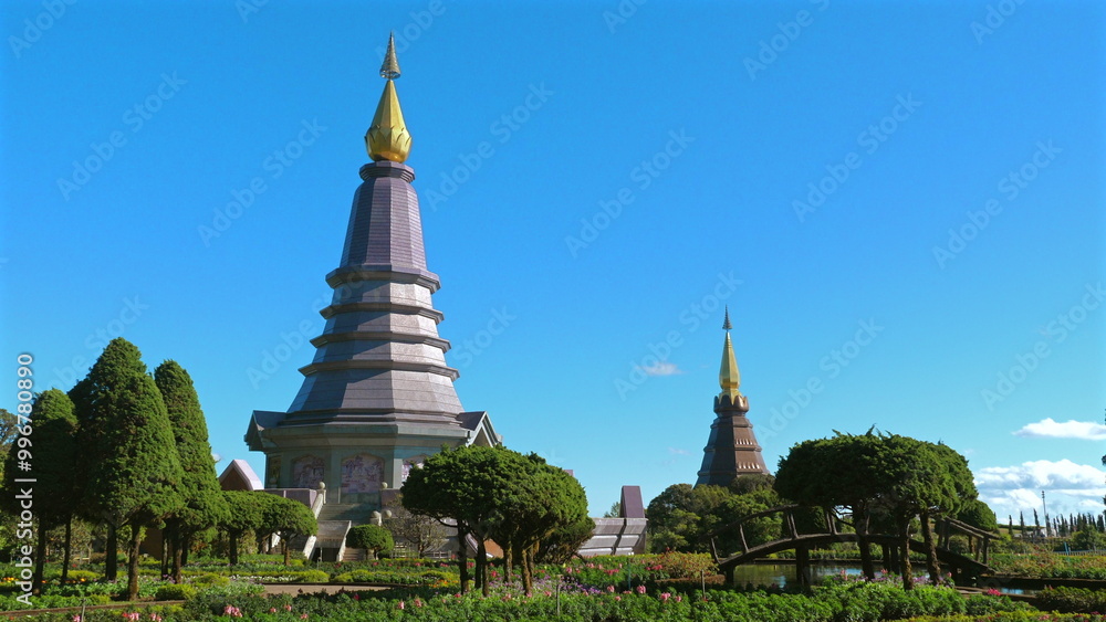 Two majestic pagodas surrounded by lush greenery under clear blue sky in Chiang Mai, Thailand. Tranquility and Architecture. Two majestic pagodas surrounded by lush greenery under clear blue sky in Chiang Mai, Thailand. Tranquility and Architecture.