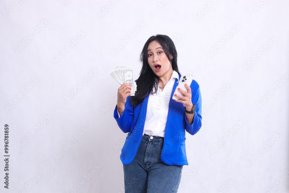 beautiful adult office girl wearing blue formal suit standing surprised to camera carrying dollar money and smartphone isolated white background. for transaction, finance, business content beautiful adult office girl wearing blue formal suit standing surprised to camera carrying dollar money and smartphone isolated white background. for transaction, finance, business content
