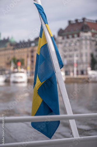 Stern flag on a harbor passenger ferry leaving the bay Nybroviken with old steam and new passenger boats, a summer day in Stockholm photo