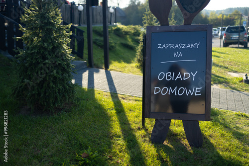 Menu of the meats of restaurant in Krakow, Poland. Outdoor advertising stand with menu against a rustic wooden background. Blank white template of a freestanding sandwich board at a farm gate. 