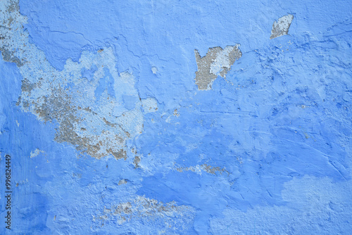 Blue wall with paint chipping off. Grunge texture with concrete underneath. 