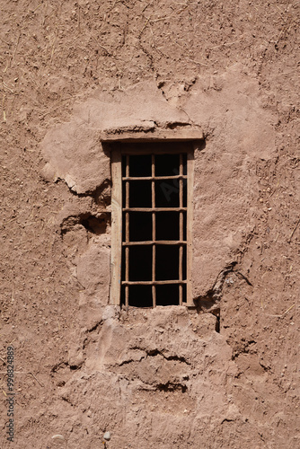 An old window with metal bars, set in a wall build of clay