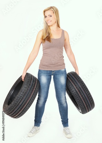 A woman is confidently holding two tires firmly in her hands