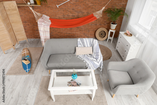 Photography Interior of stylish living room with grey sofa, surfing board and hammock