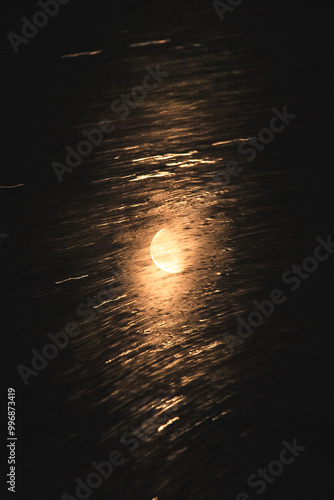 blurred water with reflection of bright orange moon (multiple exposure)