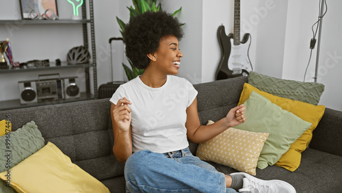 A joyful black woman lounging casually on a sofa in a cozy living room, embodying comfort and happiness. photo