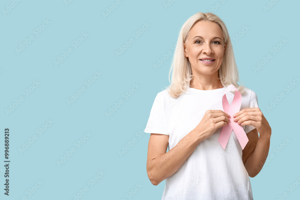 Mature woman with pink ribbon on blue background. Breast cancer awareness concept Mature woman with pink ribbon on blue background. Breast cancer awareness concept