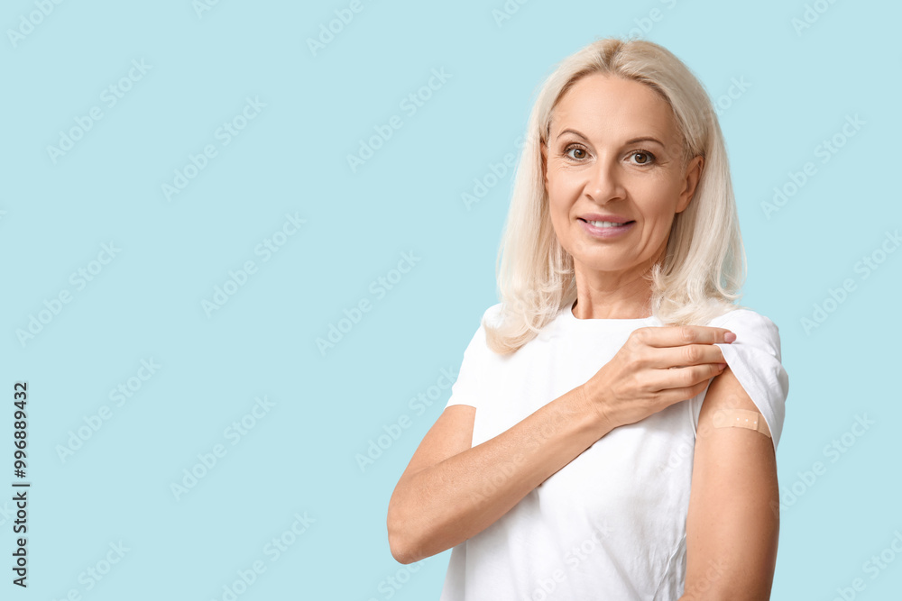 Mature woman with medical patch on arm against blue background. Vaccination concept Mature woman with medical patch on arm against blue background. Vaccination concept