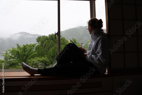 femme pensive à la fenêtre devant des montagnes