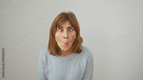 Photos Mature woman makes a funny face against a white background, showcasing personality and humor in a simple portrait