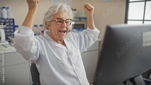 A joyful senior woman scientist celebrates success indoors at a laboratory