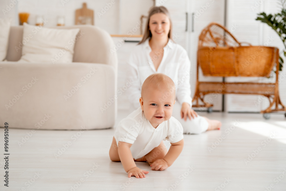a baby learns to crawl on the floor, a small child crawls, a young mother and son, happy motherhood and maternity leave, mother and baby family, parents a baby learns to crawl on the floor, a small child crawls, a young mother and son, happy motherhood and maternity leave, mother and baby family, parents