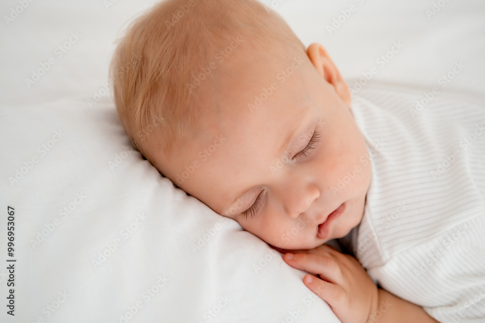 a newborn baby sleeps sweetly on his tummy, a place for text, a baby sleeps on a white bed with a pen under his cheek, a healthy baby's sleep, a close-up portrait a newborn baby sleeps sweetly on his tummy, a place for text, a baby sleeps on a white bed with a pen under his cheek, a healthy baby's sleep, a close-up portrait