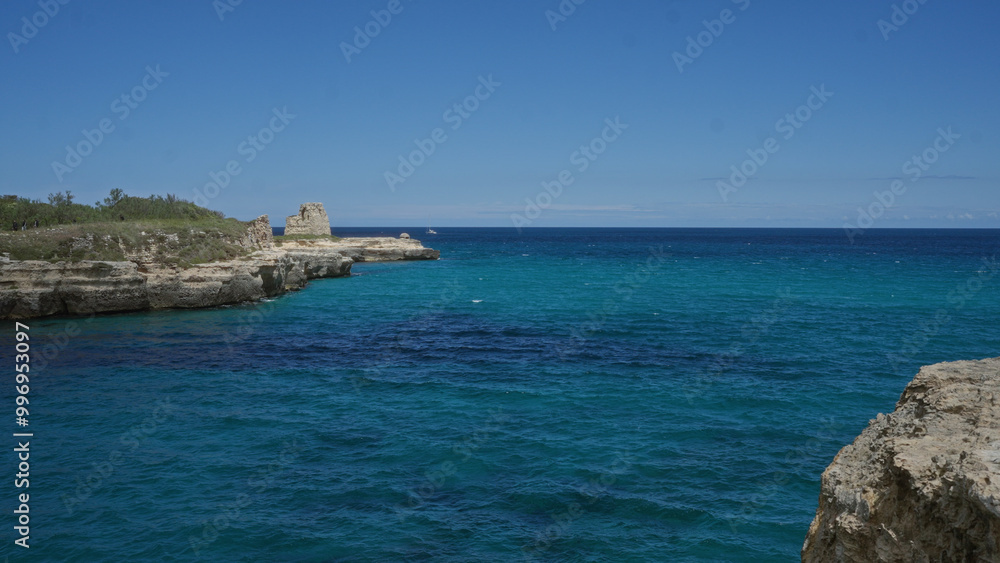 A stunning view of the turquoise waters and rocky cliffs of the cave of poetry in salento, puglia, italy, under a clear blue sky. A stunning view of the turquoise waters and rocky cliffs of the cave of poetry in salento, puglia, italy, under a clear blue sky.