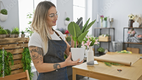 Blonde woman examines a plant indoors at a flower shop, portraying a natural, nurturing, and green ambiance.