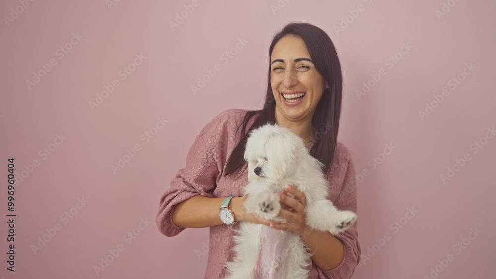 Happy woman holding a small dog against a pink background Happy woman holding a small dog against a pink background