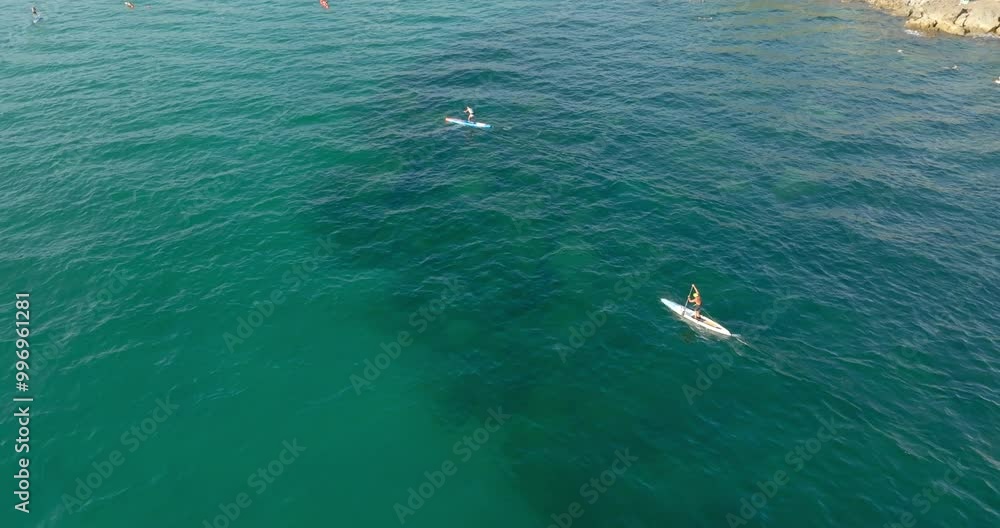 Aerial view of people surfing on a sup in the Mediterranean Sea. Aerial view of people surfing on a sup in the Mediterranean Sea.