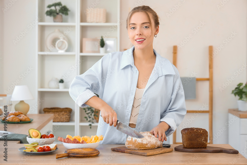 Beautiful young happy woman cutting bread for tasty toasts with butter in kitchen at home Beautiful young happy woman cutting bread for tasty toasts with butter in kitchen at home