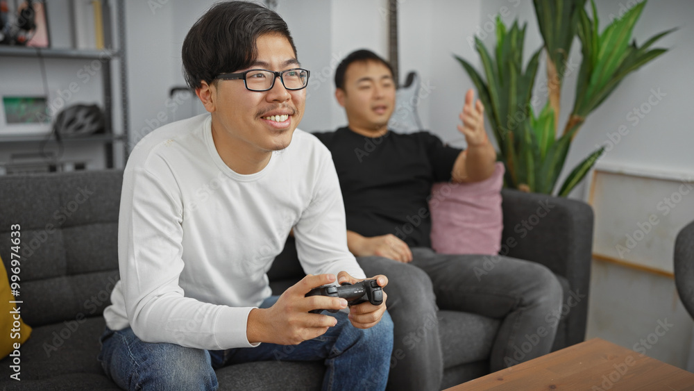 Two asian men enjoying time together playing video games in a cozy living room setting. Two asian men enjoying time together playing video games in a cozy living room setting.