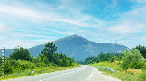 Scenic road leading towards a lush, mystic Rtanj mountain, under a clear blue sky. Serbia. photo