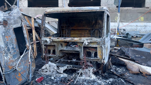 Quadro su tela Burnt-out trucks against the background of a broken building