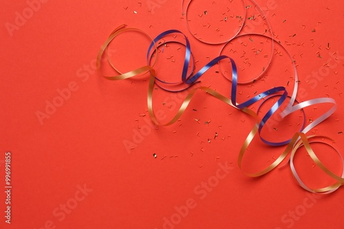 Shiny confetti and party streamers on red background, flat lay. Space for text