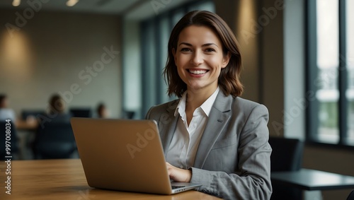 Smiling businesswoman using a laptop in a modern conference room.